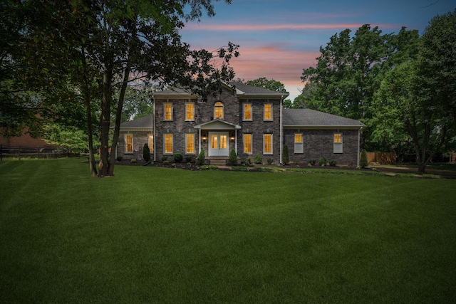 view of front of home featuring a lawn, fence, and stone siding