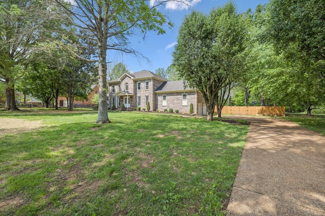 colonial home with fence, brick siding, and a front yard