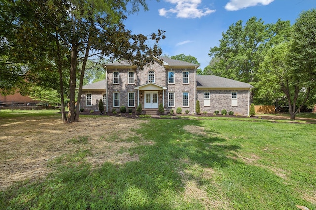 view of front of home with brick siding, a front lawn, fence, and french doors