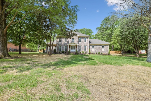 view of front of house featuring brick siding, a front lawn, and fence