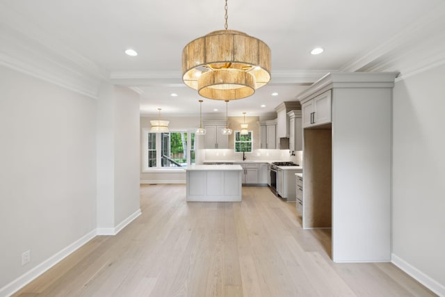 kitchen featuring light countertops, a center island, ornamental molding, and stainless steel range with gas cooktop