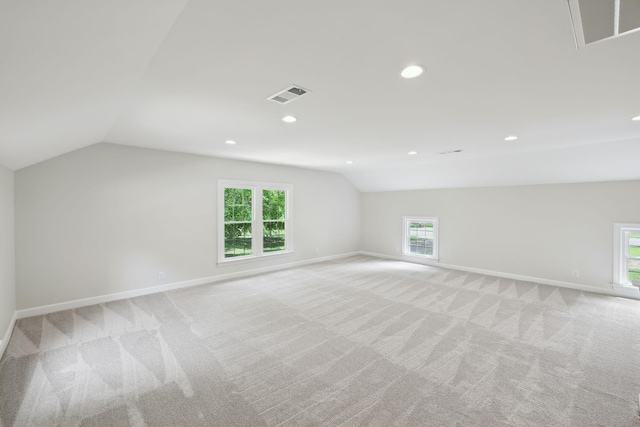 bonus room with light colored carpet, baseboards, vaulted ceiling, and visible vents