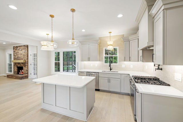 kitchen with appliances with stainless steel finishes, a sink, light wood-style floors, light countertops, and open floor plan