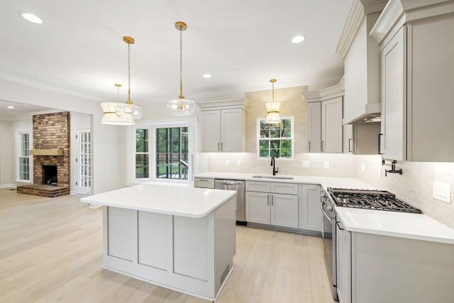 kitchen with open floor plan, light countertops, a sink, light wood finished floors, and appliances with stainless steel finishes