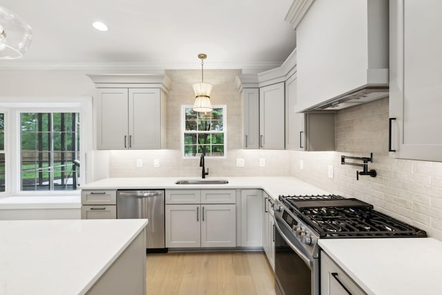 kitchen featuring crown molding, light countertops, custom range hood, a sink, and stainless steel appliances