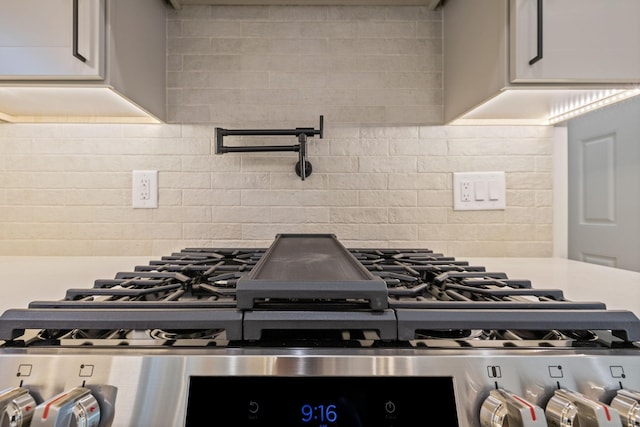 kitchen with light countertops, stainless steel gas range, and tasteful backsplash