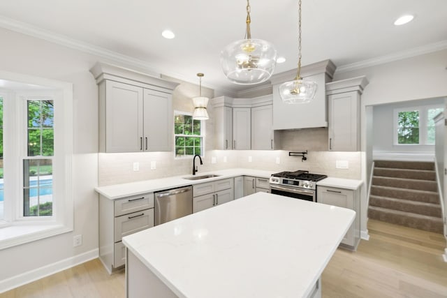 kitchen with a kitchen island, light wood-style floors, a sink, backsplash, and stainless steel appliances