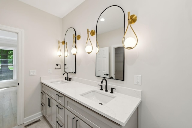 bathroom with double vanity, baseboards, visible vents, and a sink