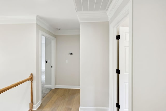 corridor featuring visible vents, ornamental molding, baseboards, light wood finished floors, and an upstairs landing