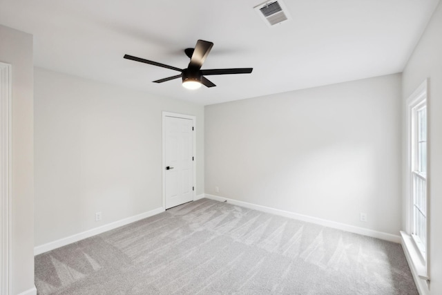empty room featuring carpet flooring, a ceiling fan, baseboards, and visible vents