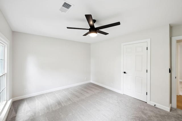 carpeted spare room with plenty of natural light, baseboards, ceiling fan, and visible vents