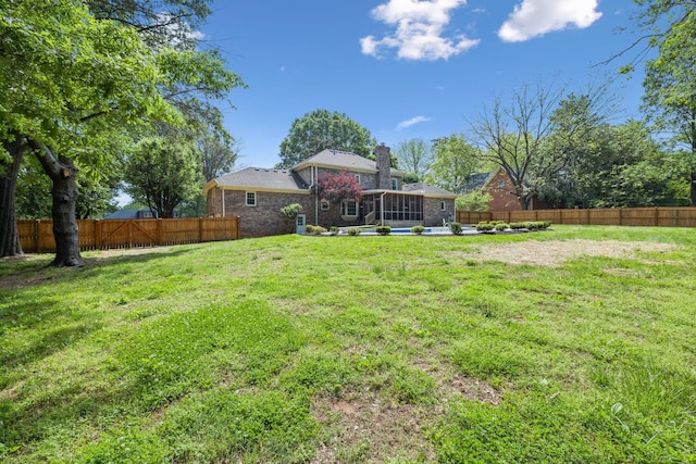 view of yard featuring a sunroom and a fenced backyard