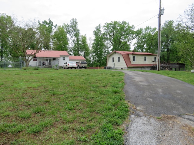 view of front of home with a front lawn, a gambrel roof, fence, and driveway