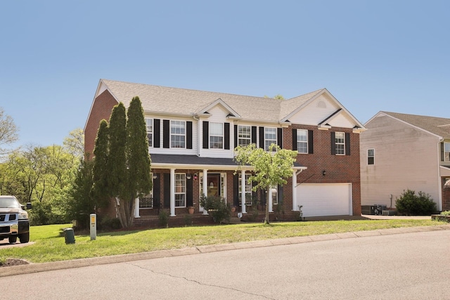 colonial-style house with an attached garage, covered porch, a front lawn, and brick siding