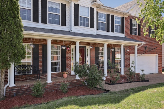 view of front facade featuring an attached garage, brick siding, and covered porch