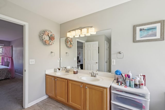 ensuite bathroom featuring baseboards, a sink, double vanity, and connected bathroom