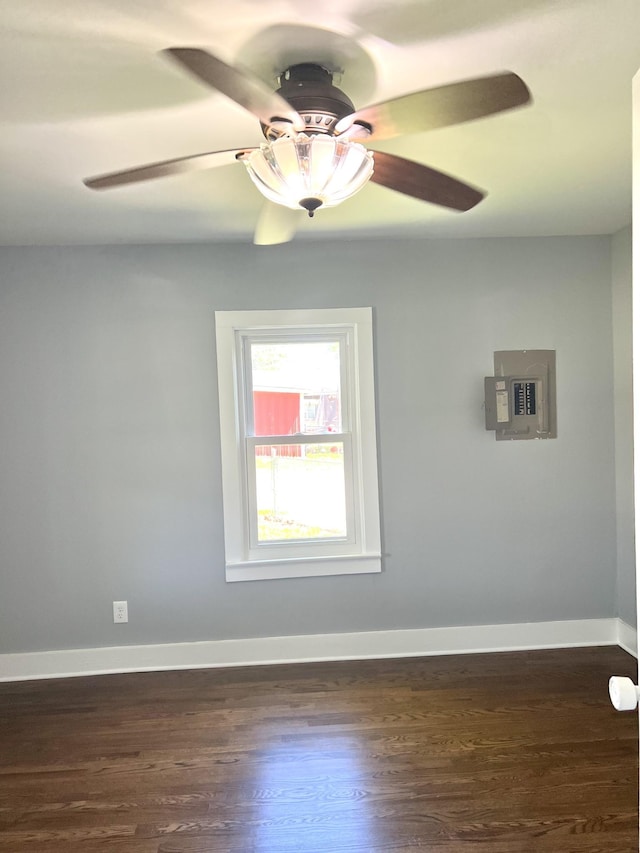 unfurnished room with dark wood finished floors, baseboards, a ceiling fan, and electric panel
