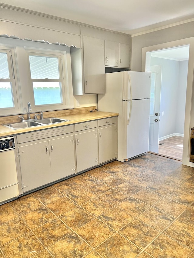 kitchen featuring light countertops, white appliances, crown molding, and a sink