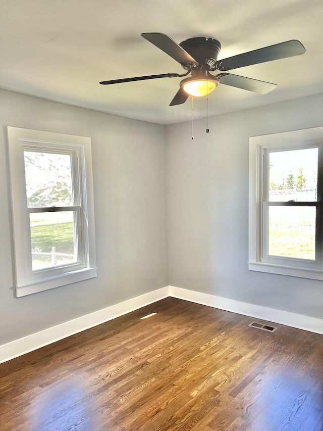 unfurnished room with baseboards, visible vents, ceiling fan, and dark wood-style flooring