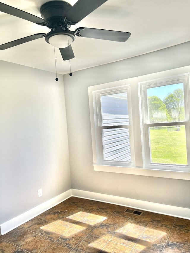unfurnished room featuring ceiling fan, baseboards, stone finish floor, and visible vents