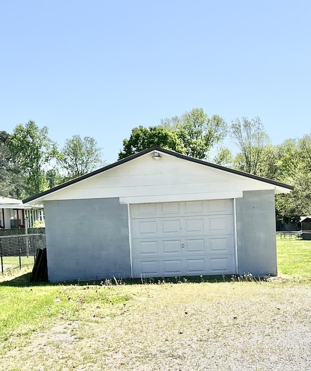 detached garage featuring fence and driveway