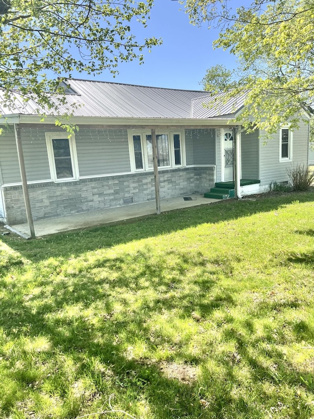 view of front of home featuring a front lawn, entry steps, and metal roof