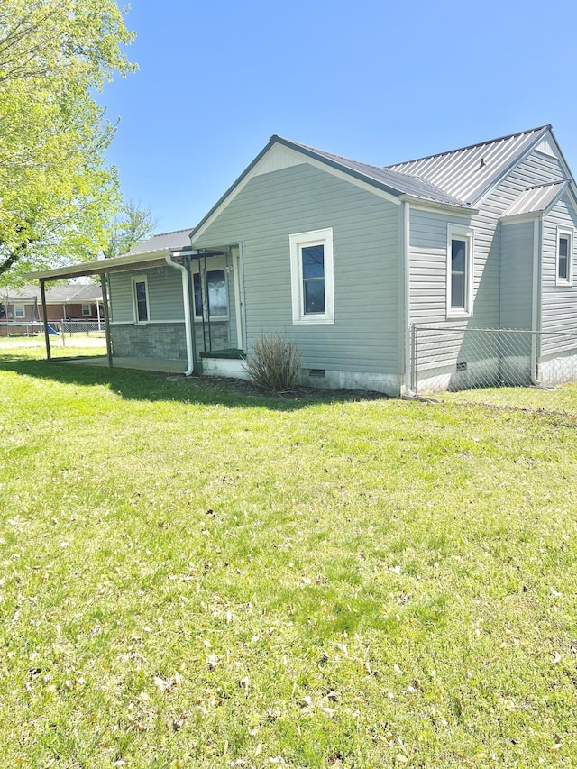 rear view of property featuring crawl space, a lawn, and metal roof