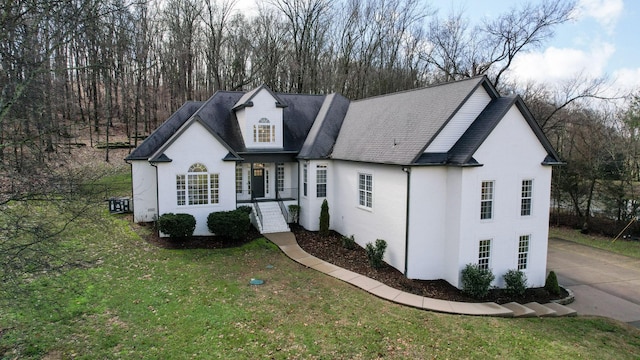 view of front facade featuring stucco siding, concrete driveway, a shingled roof, and a front yard