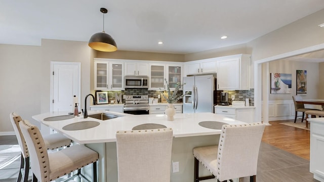 kitchen with backsplash, appliances with stainless steel finishes, a kitchen breakfast bar, and a sink