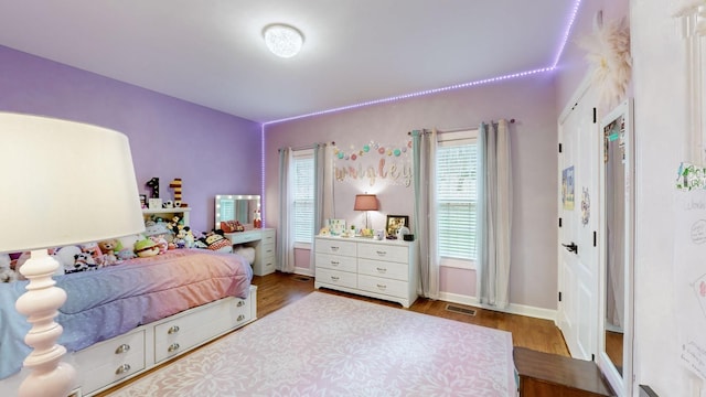 bedroom featuring baseboards, wood finished floors, and visible vents