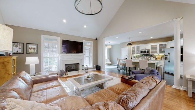 living room featuring recessed lighting, a high end fireplace, light wood-style floors, and high vaulted ceiling
