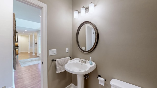 bathroom with toilet, wood finished floors, and baseboards