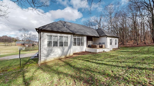 rear view of property with fence, a lawn, and stucco siding