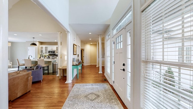 entryway with plenty of natural light, wood finished floors, and ornate columns