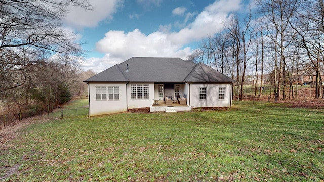 back of property featuring fence, stucco siding, a patio, a lawn, and roof with shingles