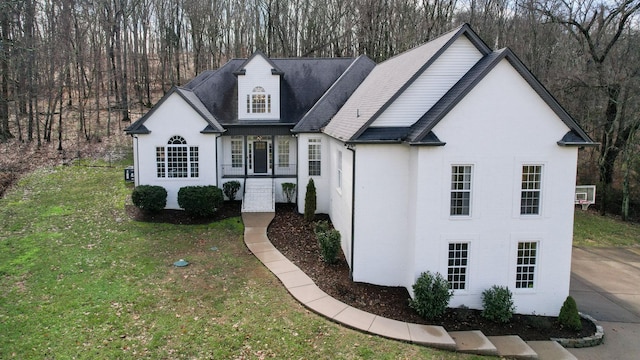 view of front of house featuring an AC wall unit, a shingled roof, brick siding, and a front yard