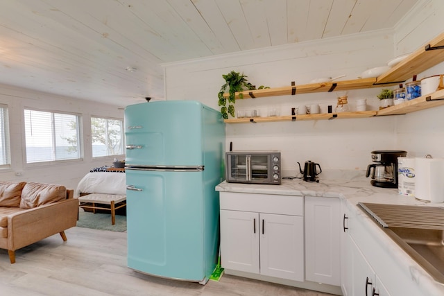 kitchen featuring open shelves, a toaster, light wood finished floors, wooden ceiling, and freestanding refrigerator