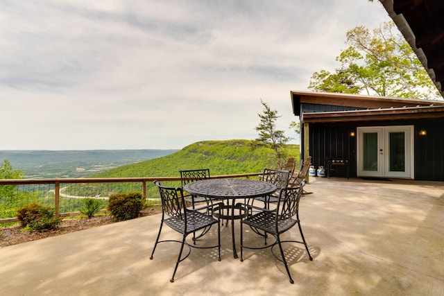 view of patio / terrace featuring french doors, outdoor dining area, and a mountain view