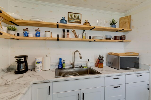 kitchen featuring open shelves, white cabinets, ornamental molding, and a sink