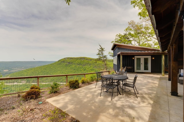 view of patio / terrace featuring outdoor dining area, french doors, and a mountain view