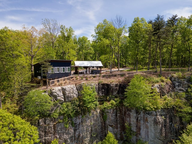 back of property featuring a forest view and an outbuilding