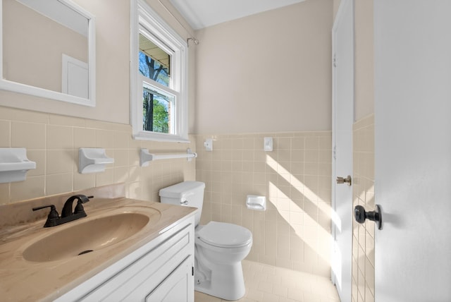 bathroom featuring tile walls, a wainscoted wall, vanity, and toilet