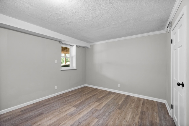 unfurnished room with baseboards, wood finished floors, a textured ceiling, and ornamental molding