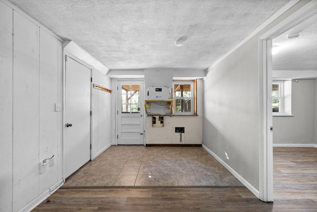 foyer featuring baseboards, wood finished floors, and a textured ceiling