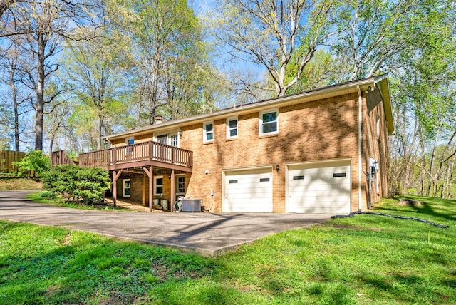 back of property featuring brick siding, an attached garage, aphalt driveway, and a deck