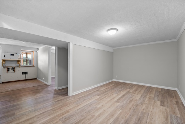 below grade area with light wood-style floors, a textured ceiling, crown molding, and baseboards