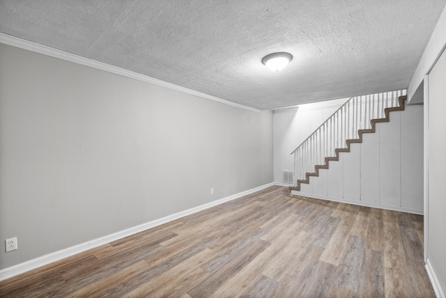 finished basement with a textured ceiling, visible vents, baseboards, wood finished floors, and stairs