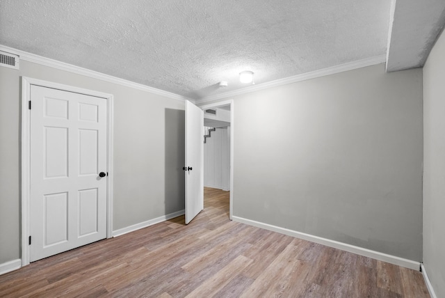 unfurnished bedroom featuring baseboards, wood finished floors, a textured ceiling, and ornamental molding