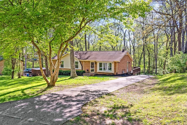 tri-level home with concrete driveway, brick siding, and a front yard