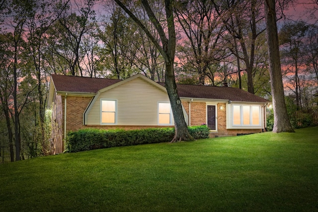 ranch-style house featuring brick siding, roof with shingles, a chimney, and a front lawn